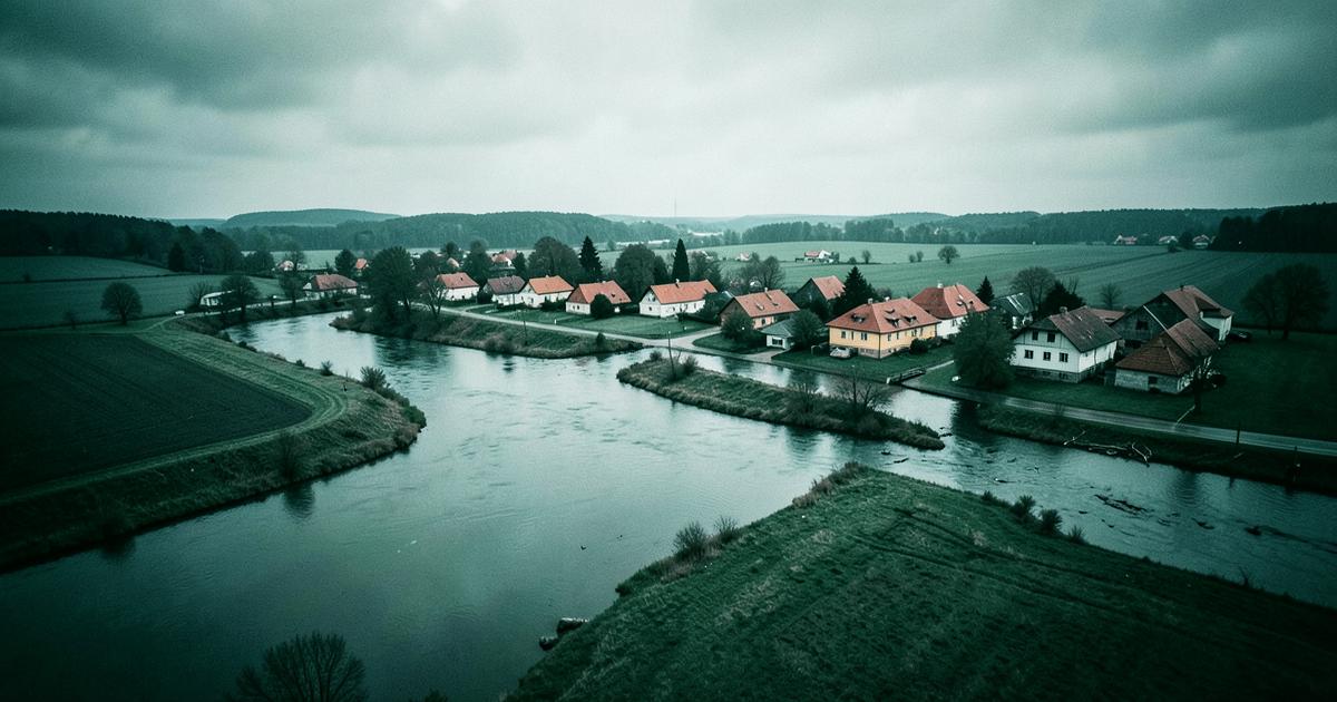 Letecký pohled na řeku rozvodněnou po deštích, voda v nivě u vesnice s rodinnými domy